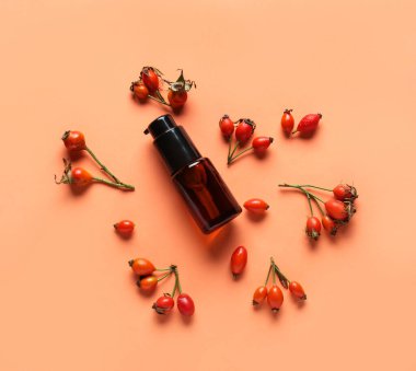 Renkli arkaplanda kozmetik ürünler ve gül kalçası çilekleri olan kompozisyon