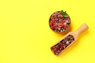 Sarı arka planda tatlı şekerli yaban mersinli kase ve kepçe