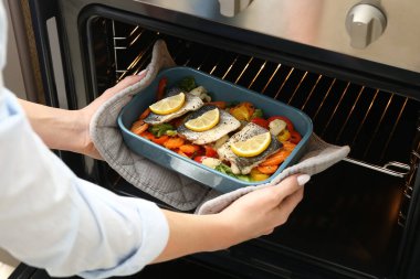 Mutfakta lezzetli levrek balığıyla fırından çıkan kadın.