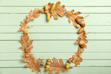 Kuru meşe yapraklarından yapılmış çerçeve ve ahşap arkaplanda meşe palamudu