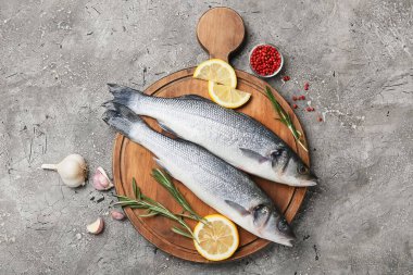 Ahşap tahta tahta tahta, taze levrek balığı ve arkaplanda limon.