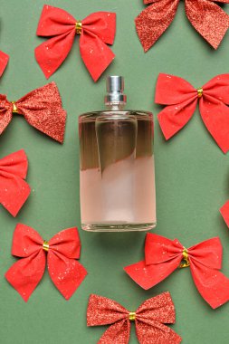 Bir şişe parfüm ve yeşil arka planda Noel yayları, yakın plan.