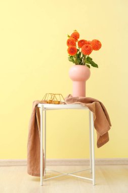 Çiçekli vazolar ve renkli duvarların yanındaki masada mumlar.