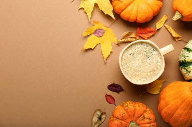 Kahverengi arka planda bir fincan kahve ve balkabağı kompozisyonu