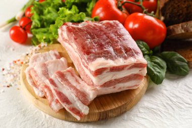 Beyaz arka planda pişmemiş pastırmalı ahşap tahta.