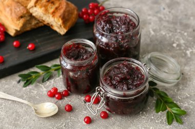 Gri arka planda lezzetli yaban mersini reçeli kavanozları