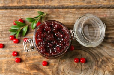 Ahşap arka planda bir kavanoz lezzetli yaban mersini reçeli.