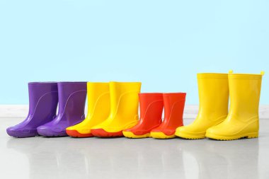 Renkli duvarın yanında yerde bir sürü lastik bot var.