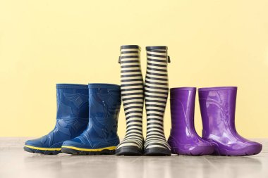 Renkli duvarın yanında yerde farklı lastik çizmeler var.