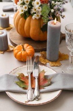 Balkabağında güzel sonbahar çiçekleri ve servis masasında yanan mumlar.