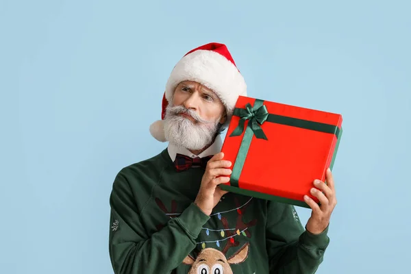 Старший Человек Шляпе Санты Рождественский Свитер Держа Подарок Цветном Фоне — стоковое фото