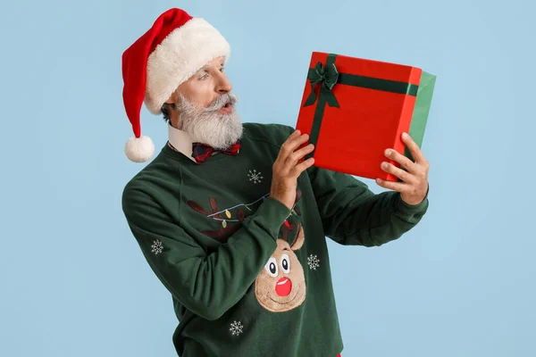 Удивленный Пожилой Человек Шляпе Санты Рождественский Свитер Держа Подарок Цветном — стоковое фото