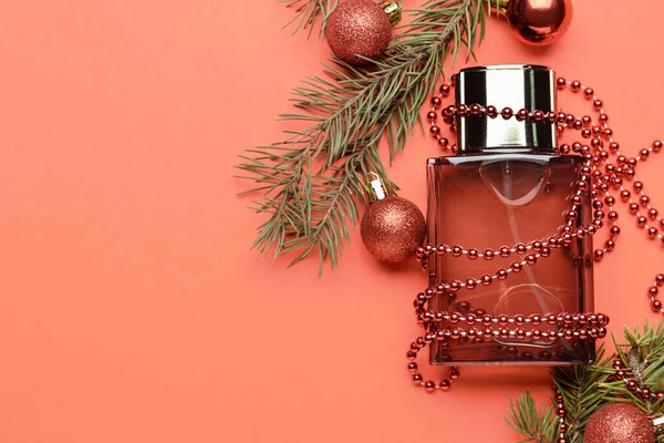 Bir şişe parfüm, köknar ağacı dalı ve arka planda Noel dekoru.