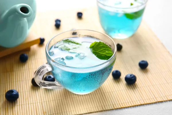 Glass cup of iced blue tea with blueberry on light background, closeup