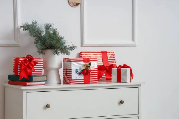 Комод Різдвяними Подарунковими Коробками Ялиновими Гілками Біля Світлої Стіни — стокове фото
