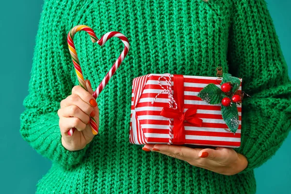 緑の背景にクリスマスプレゼントやキャンディーの杖を持つ女性 クローズアップ — ストック写真