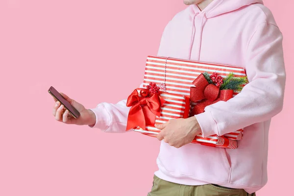 Άνδρας Κουτιά Δώρων Χριστουγέννων Χρησιμοποιώντας Κινητό Τηλέφωνο Ροζ Φόντο — Φωτογραφία Αρχείου