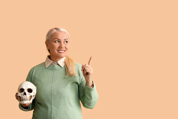 人間の頭蓋骨を持ち 色の背景に何かを指している女性 — ストック写真