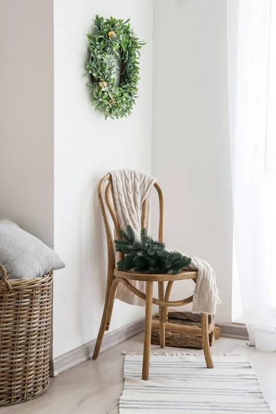 モミの枝と光の壁にぶら下がっているミステリーリースと木製の椅子 — ストック写真