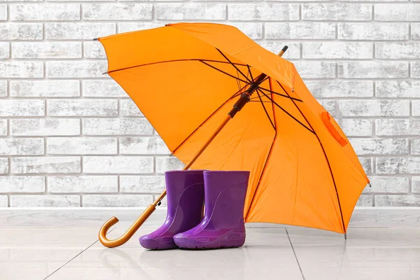 Par Gummistövlar Och Paraply Nära Tegelvägg — Stockfoto