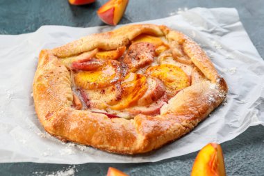 Koyu arkaplanda lezzetli şeftali galeti olan parşömen, yakın plan.