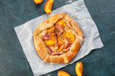 Koyu arkaplanda lezzetli şeftali galeti olan parşömen.