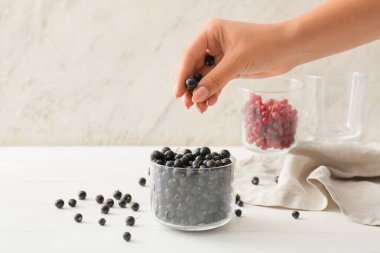 Hafif ahşap arka planda lezzetli siyah üzümlü kadın eli