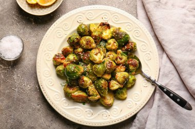 Lezzetli kızarmış Brüksel lahanası ve gri arka planda deniz tuzu tabağı