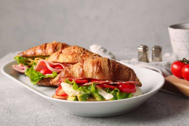 Gri arka planda lezzetli kruvasan sandviçli tabak.