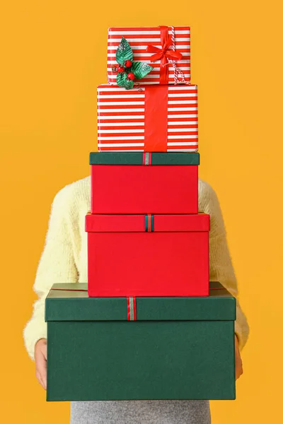 黄色の背景にクリスマスのギフトボックスを保持女性 — ストック写真