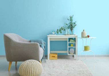 Mavi duvarın yanındaki masada okaliptüs dallı vazolar.