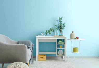 Mavi duvarın yanındaki masada okaliptüs dallı vazolar.