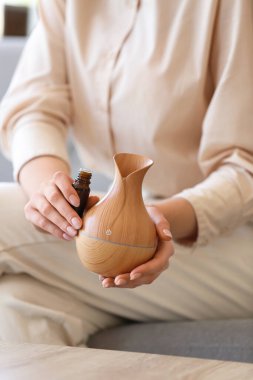 Yağ şişesi ve difüzörlü kadın elleri, yakın plan.