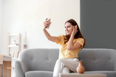 Kanepede oturup selfie çeken güzel bir kadın.