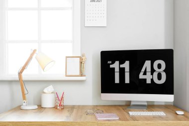 Işık duvarının yanında bilgisayar ve lamba olan ahşap masa