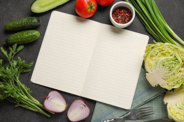 Açılan tarif kitabı ve koyu arkaplanda farklı malzemeler