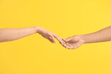 Erkek ve kadın sarı arka planda parmaklarına dokunuyor