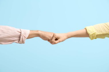Erkek ve kadın mavi arka planda yumruk tokuşturuyor