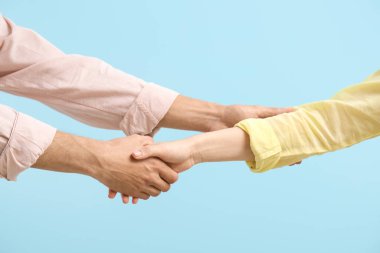 Adamın biri mavi arka planda kadının elini sıkıyor.