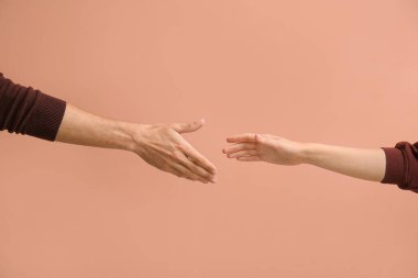 Woman and man reaching out to handshake on beige background clipart