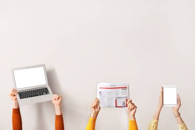 Işık arkaplanda gazete, dizüstü bilgisayar ve tablet bilgisayara sahip kişiler