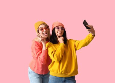 Renkli arka planda selfie çeken havalı genç kadınlar.