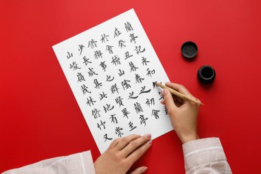 Asyalı kaligrafi yazarı renk arkaplanına hiyeroglifler yazıyor