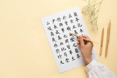 Asyalı kaligrafi yazarı renk arkaplanına hiyeroglifler yazıyor