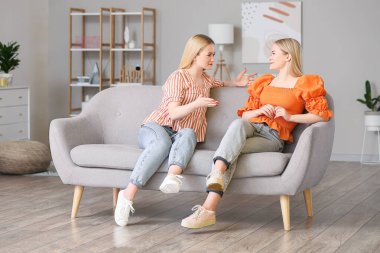 Genç ikiz kardeşler evdeki kanepede oturuyor.