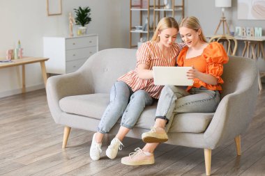 Evde dizüstü bilgisayar kullanan genç ikiz kardeşler.