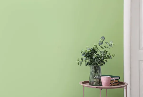 Wazon Gałęziami Eukaliptusa Filiżanka Herbaty Książki Stole Pobliżu Ściany Kolor — Zdjęcie stockowe