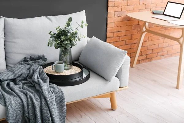 Okaliptüs dallı vazo ve odadaki kanepede bir fincan çay.