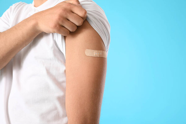 Man with medical patch on his arm against color background