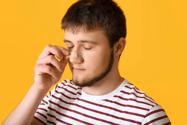 Hombre Quitando Parche Médico Nariz Contra Fondo Color — Foto de Stock